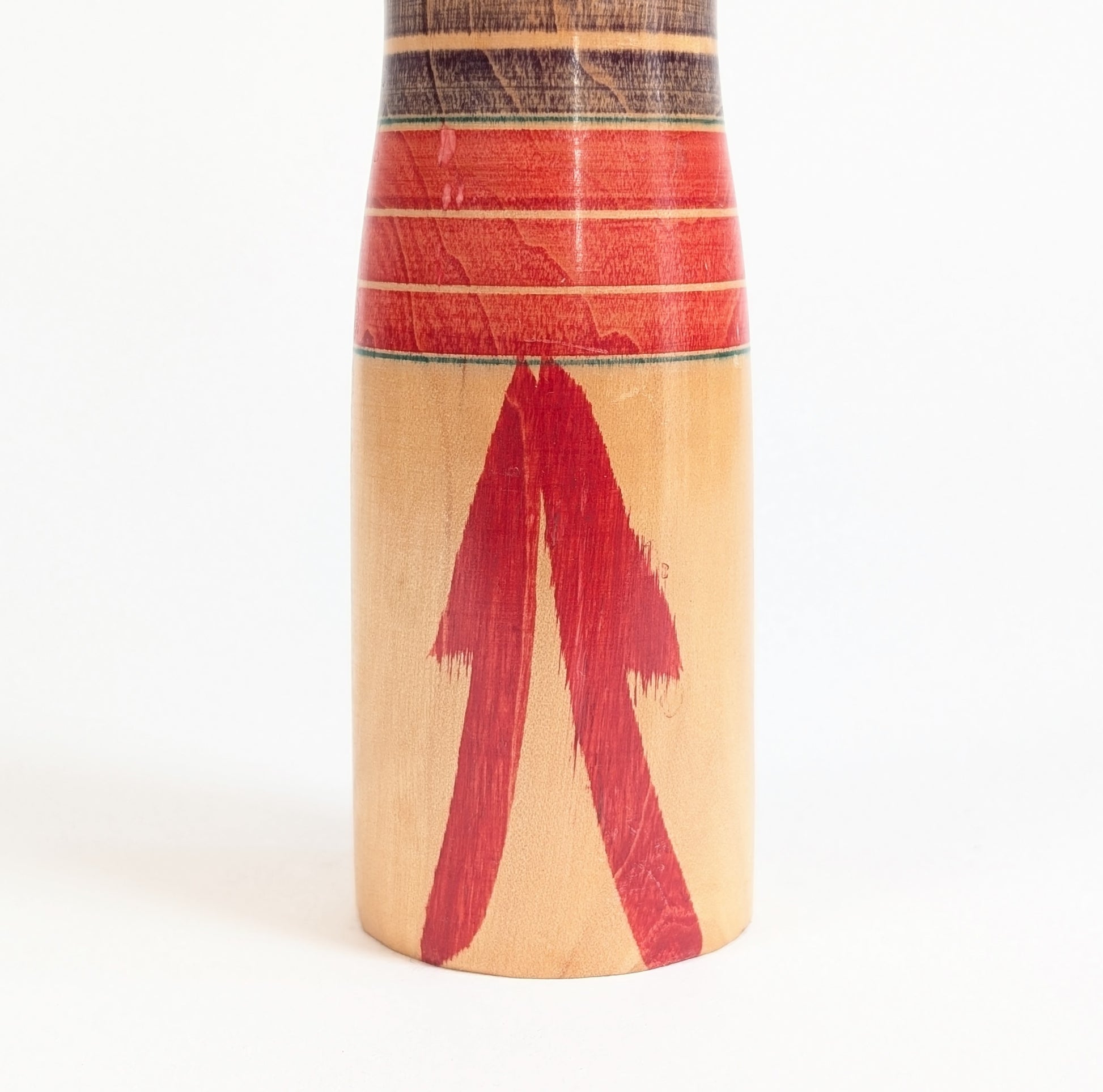 Détail du décor rouge peint à la main sur le bas du corps d’une dento kokeshi traditionnelle Yajiro