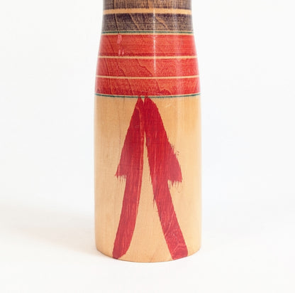 Détail du décor rouge peint à la main sur le bas du corps d’une dento kokeshi traditionnelle Yajiro