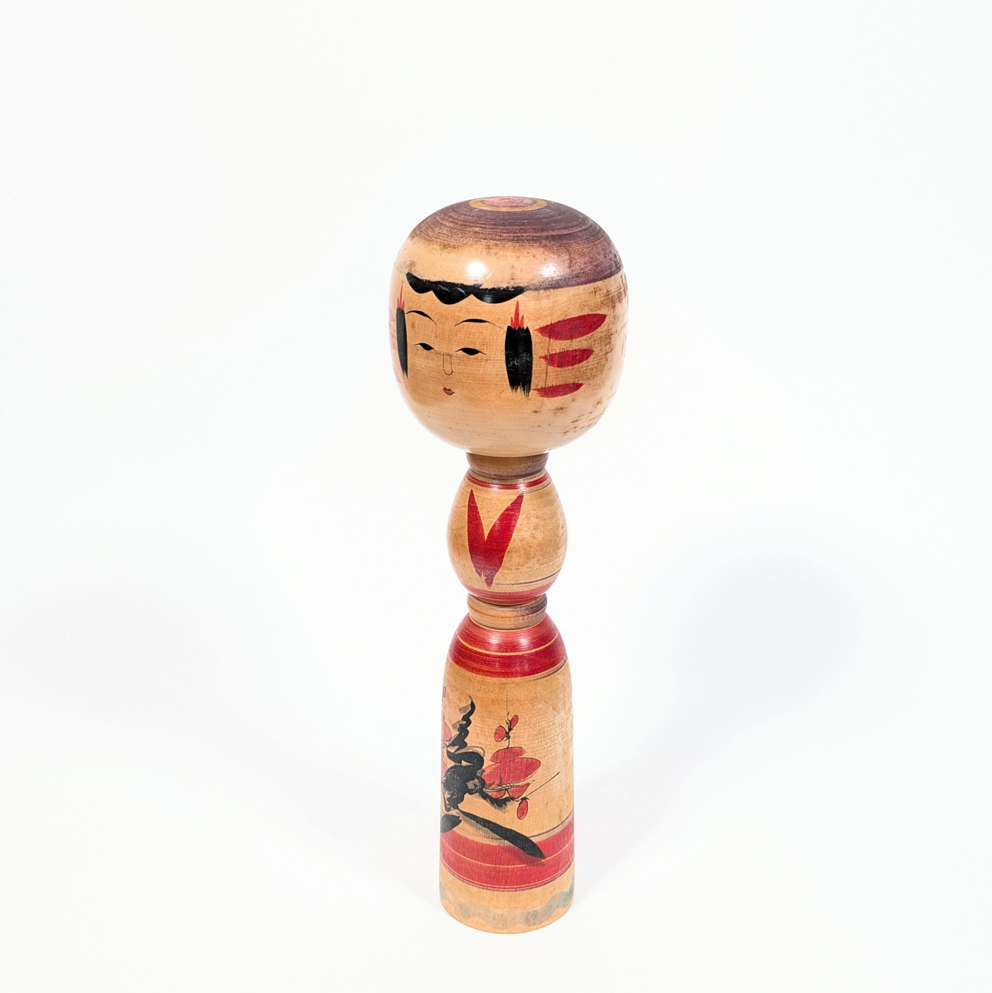 Dentō kokeshi Yajirō par Ogura Katsushi, vue de trois quarts montrant le visage délicat et le décor floral ume