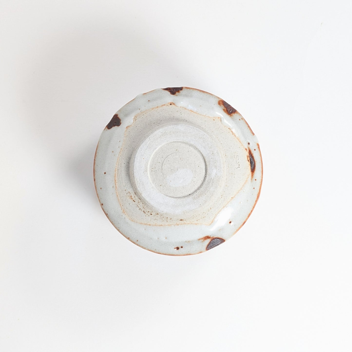 Vue du dessous du chawan Beni Shino avec pied annulaire, marques de tournage, glaçure Shino et signature du four Keizan-gama 桂山窯.