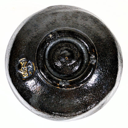 Vue du dessous d’un chawan en raku noir, montrant le pied tourné et la marque du potier Sasaki Shoraku.