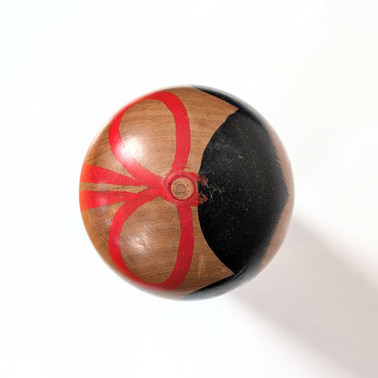 Vue du dessus de la tête d’une kokeshi japonaise traditionnelle Kijiyama, peinture artisanale noire et rouge sur bois de yamazakura