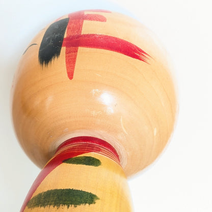Détail arrière de la tête d’une grande kokeshi dentō Yajirō par Niiyama Hisashirō, bois verni avec motifs rouges peints à la main et patine vintage