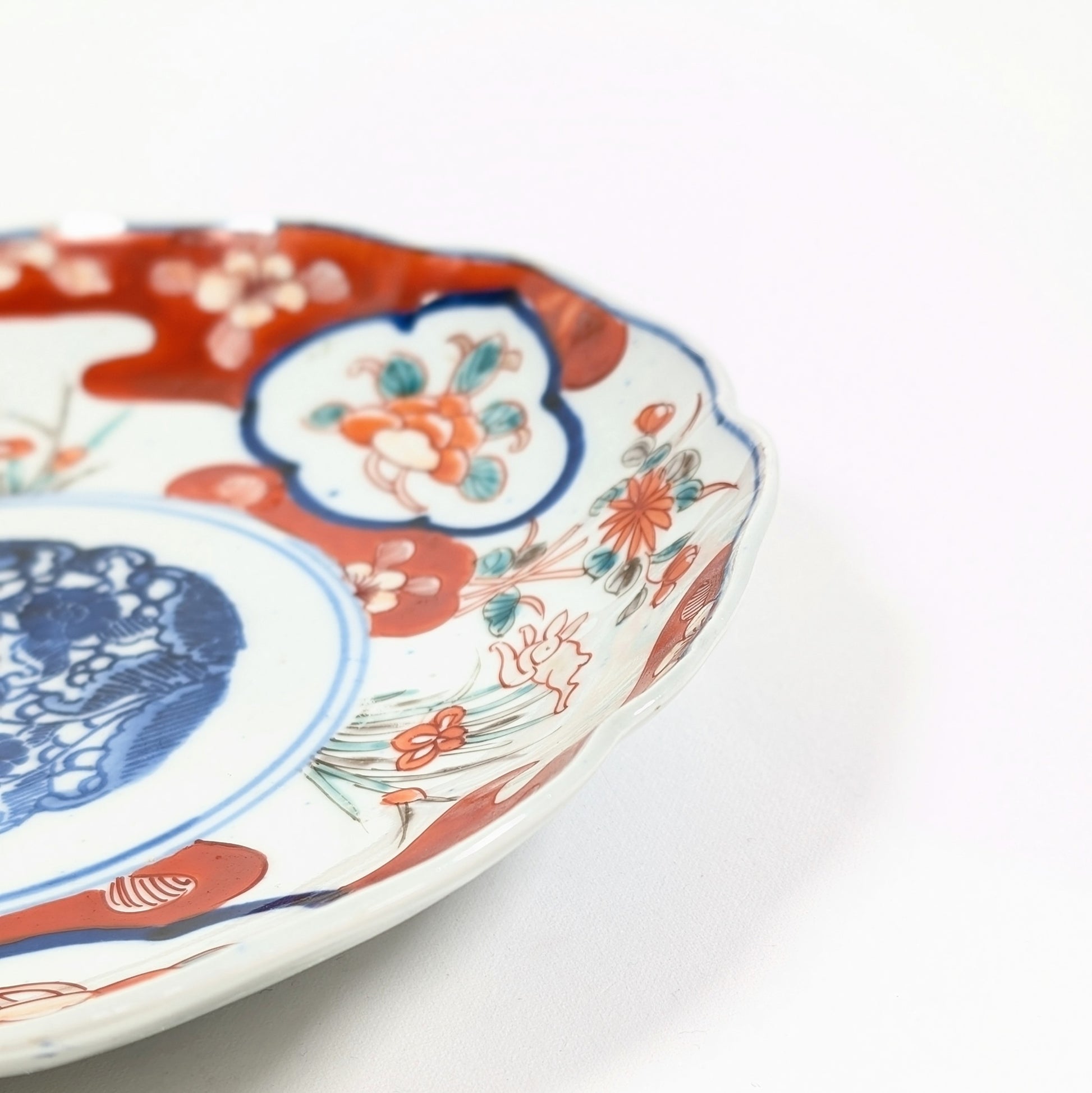 Gros plan sur le bord d’une assiette Imari antiquité avec décor floral et lapin en porcelaine japonaise