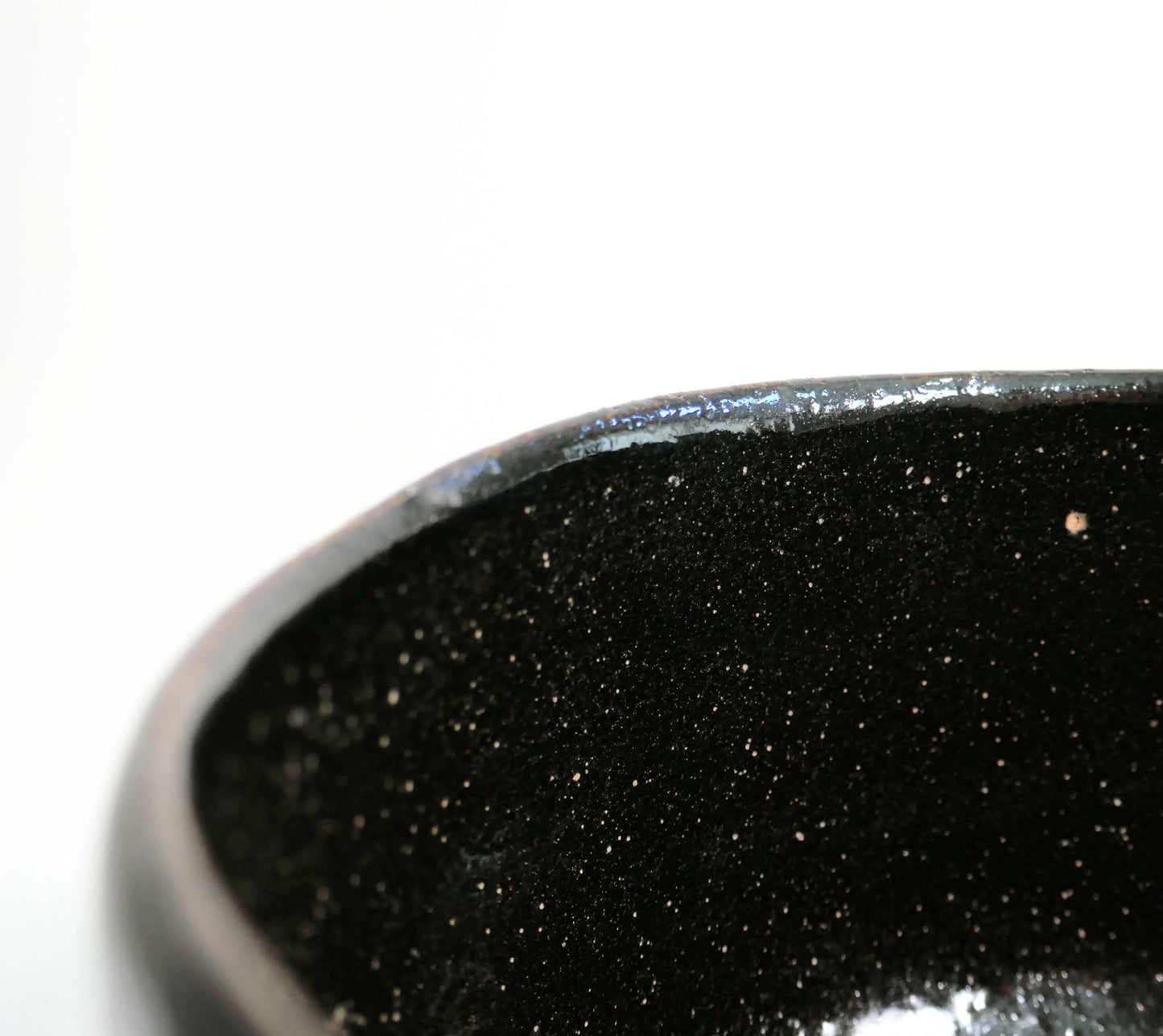 Détail du bord irrégulier du matcha chawan 抹茶碗, bol japonais en raku noir aux fines inclusions claires.
