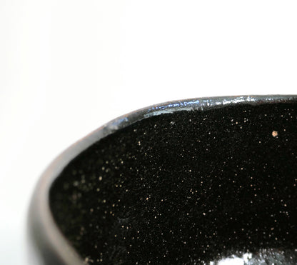 Détail du bord irrégulier du matcha chawan 抹茶碗, bol japonais en raku noir aux fines inclusions claires.
