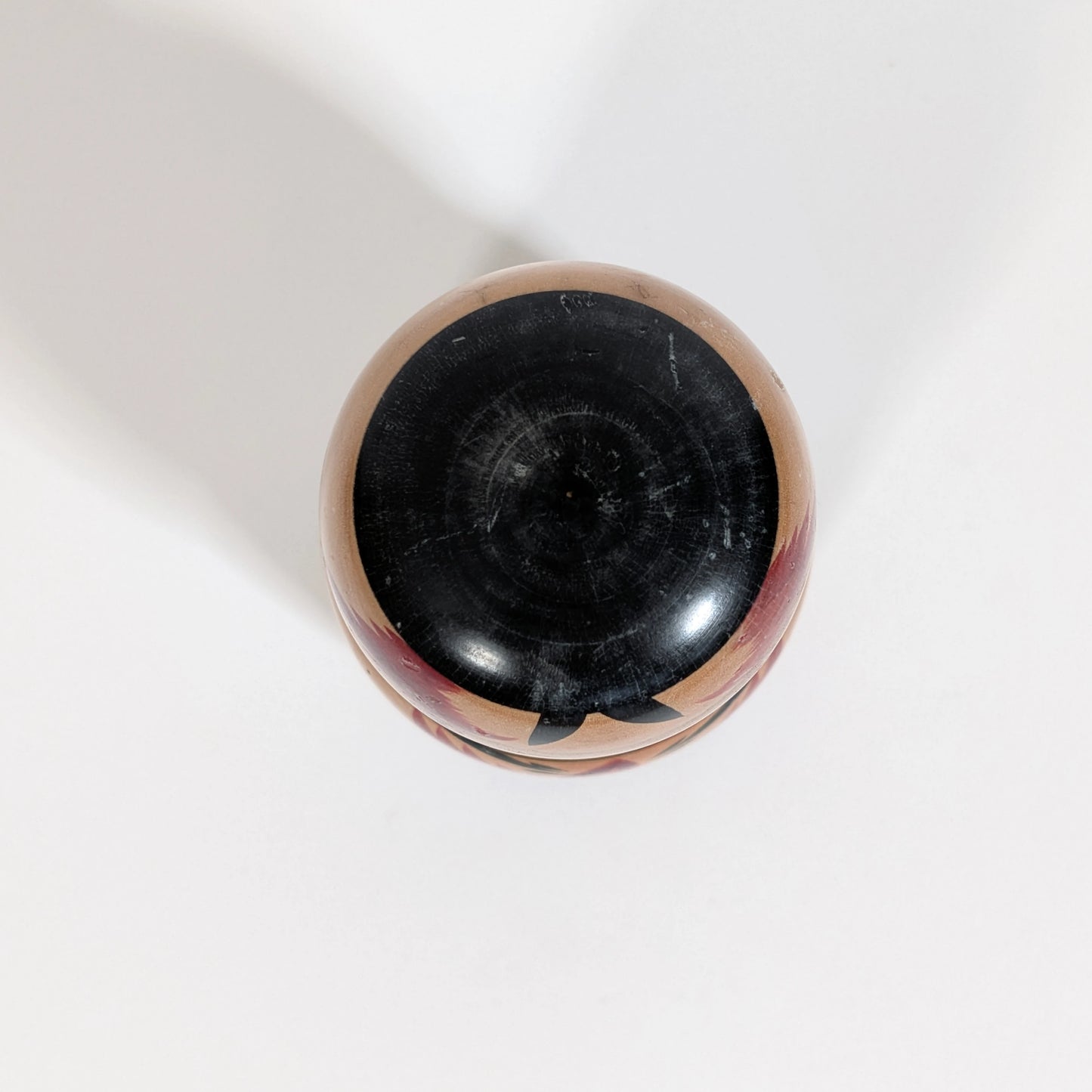 Détail de la peinture noire sur la coiffe d’une poupée japonaise kokeshi