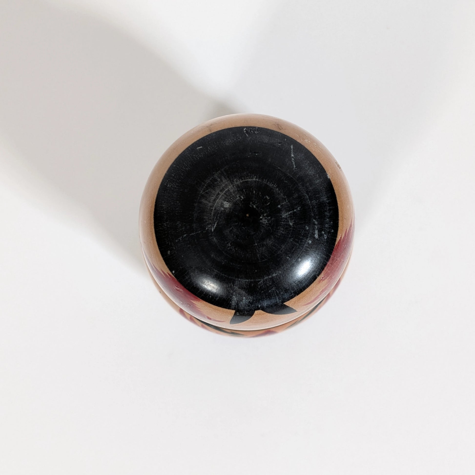 Détail de la peinture noire sur la coiffe d’une poupée japonaise kokeshi