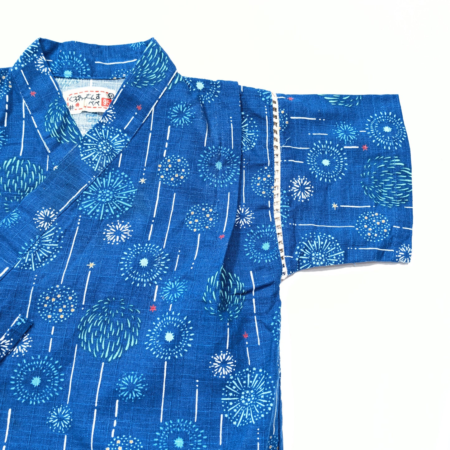 Détail du col croisé et de la manche du jinbei japonais enfant, coton bleu motif hanabi.