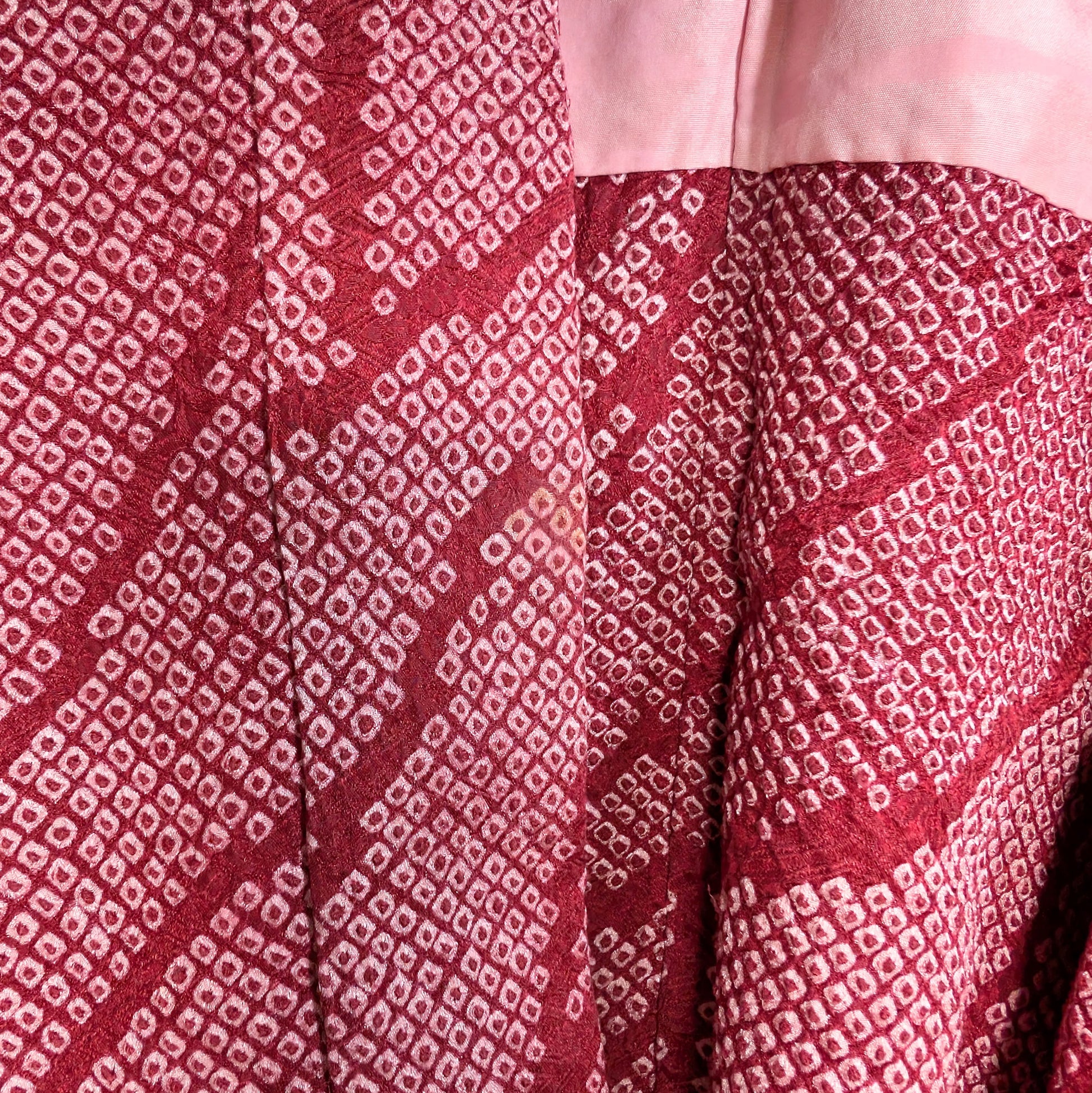 Détail du col d’un haori japonais ancien en soie shibori rose fuchsia, présentant une légère trace du temps, témoin de son authenticité.