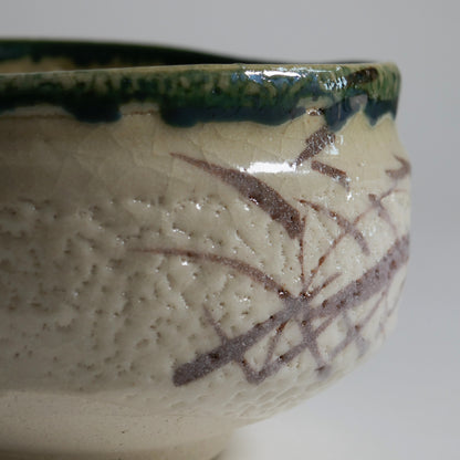 Détail de la glaçure Oribe verte et du décor brun sur un chawan japonais artisanal pour la cérémonie du thé