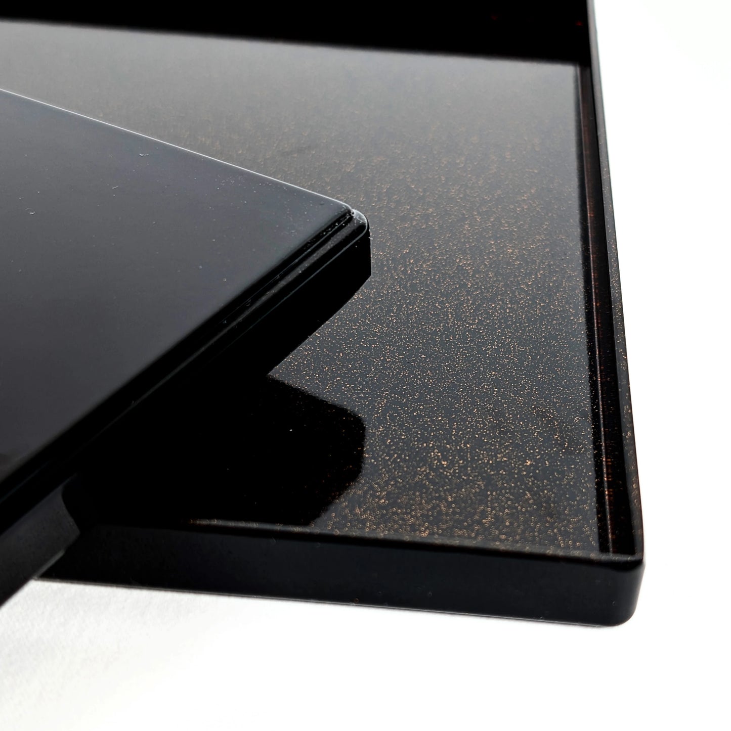 Détail du plateau intérieur en laque noire avec effet nashiji (poussière d’or), bord et angle.