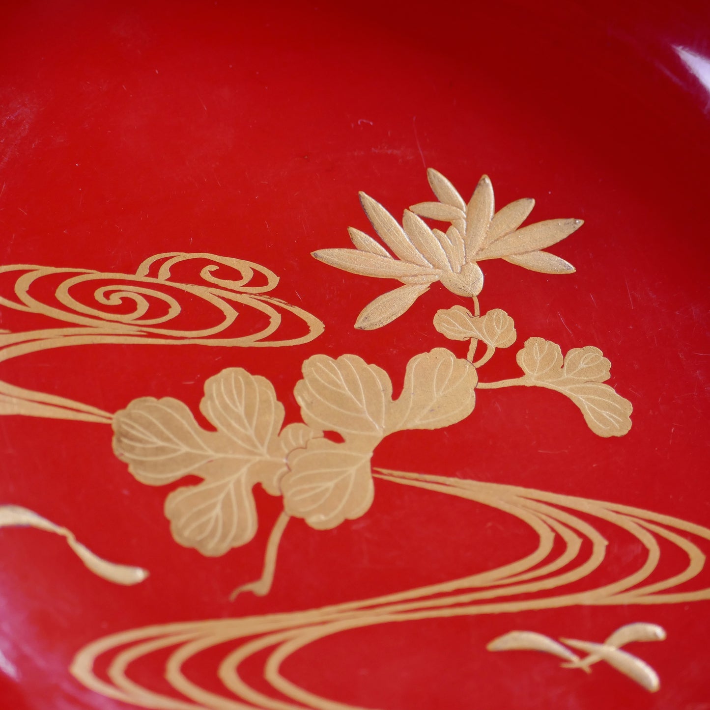 Détail du décor intérieur du couvercle associant chrysanthème kiku et lignes d’eau ryūsui en maki-e doré.