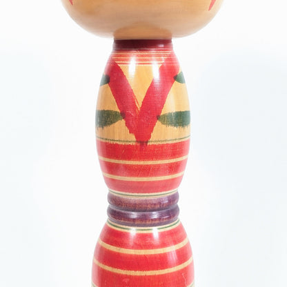 Détail du kimono stylisé d’une kokeshi dentō Yajirō, motifs rouges et verts peints à la main sur poupée japonaise traditionnelle