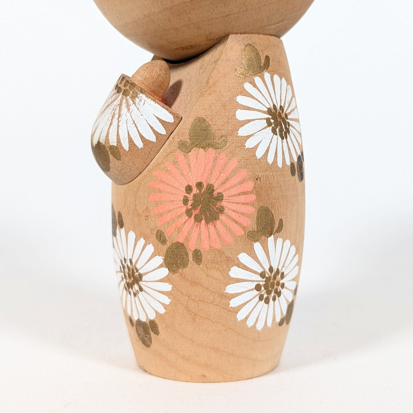 detail motif floral japonais marguerite sur kokeshi d'aoki ryoka, peinture artisanale bois naturel