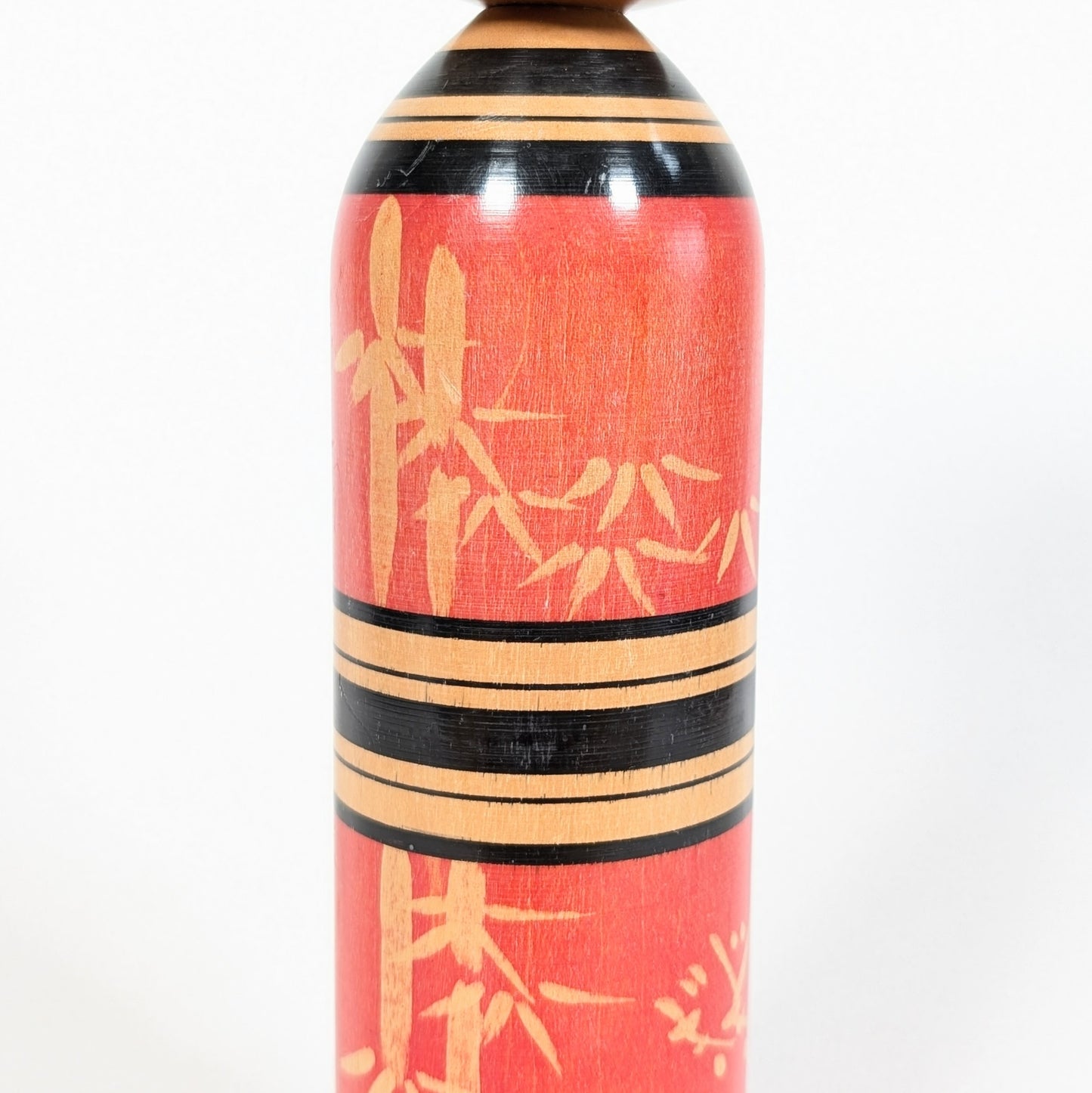 Détail du décor bambou take sur une kokeshi rouge japonaise en bois