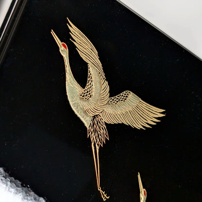 Détail d’une grue dorée (tsuru) en maki-e, ailes déployées sur fond laqué noir.