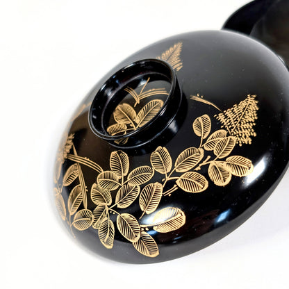 Détail maki-e doré motif hagi sur laque urushi noire, artisanat traditionnel Wajima, antiquité japonaise haut de gamme.