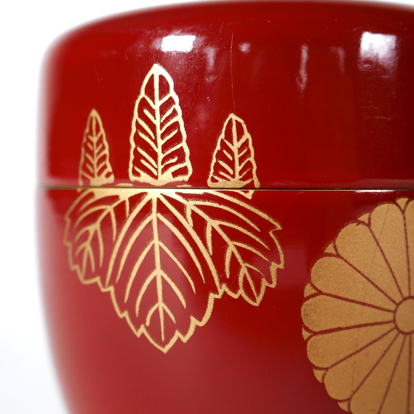 Détail du motif kiri, feuilles de paulownia dorées au pochoir kindai maki-e sur natsume japonais en laque rouge