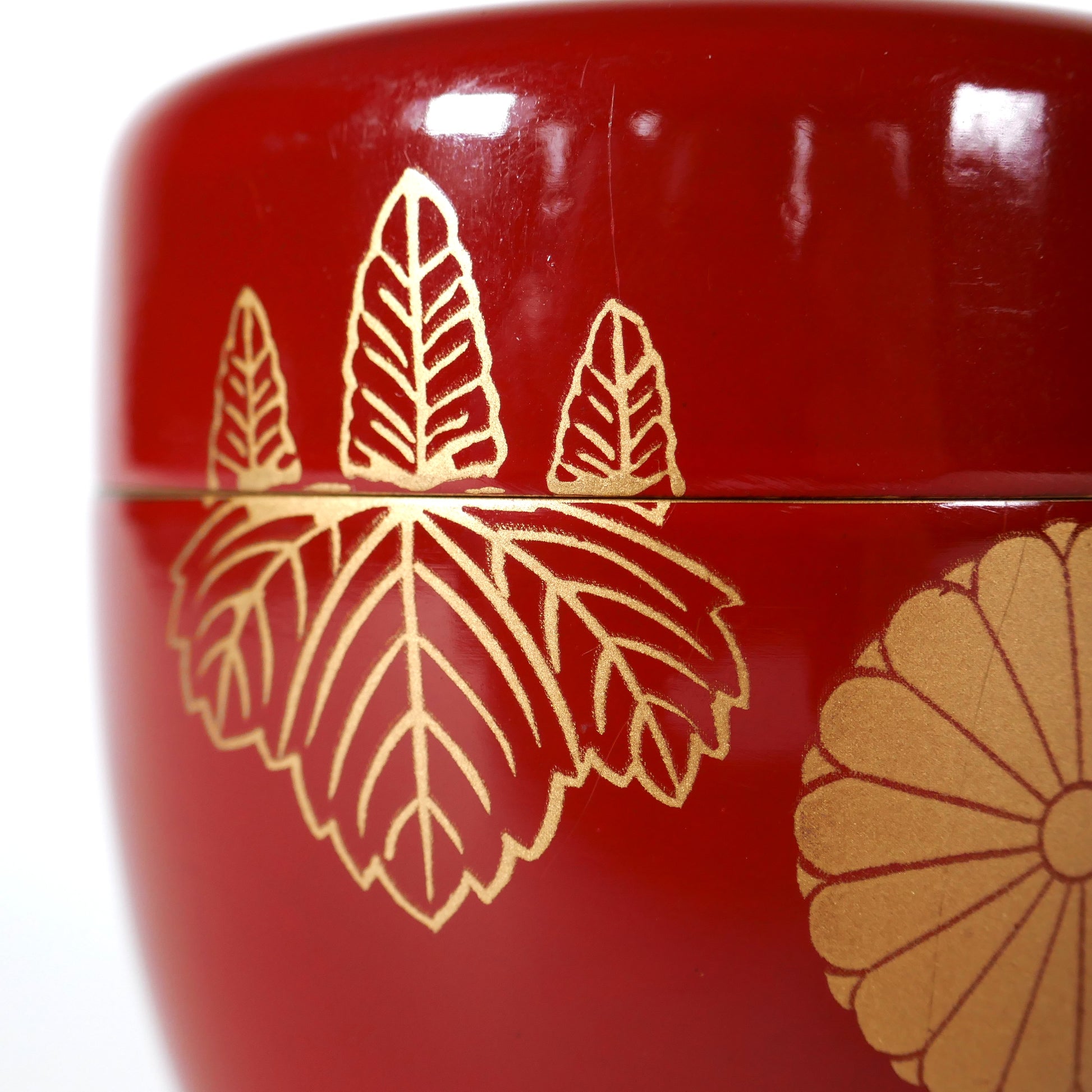 Détail du motif kiri, feuilles de paulownia dorées au pochoir kindai maki-e sur natsume japonais en laque rouge
