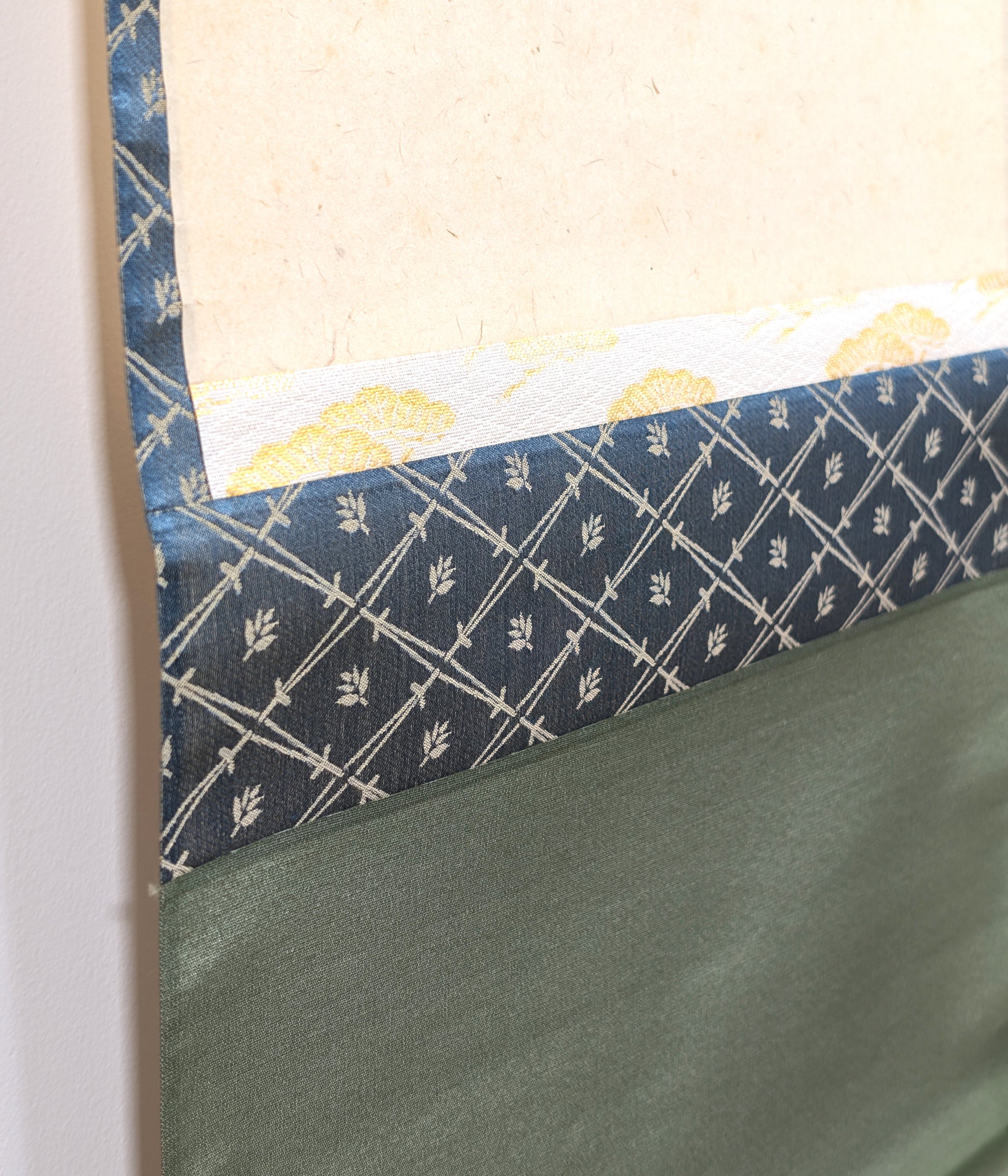 Détail du montage en soie d’un kakejiku japonais, avec papier washi, ichimonji doré et chūberi bleu à motif végétal