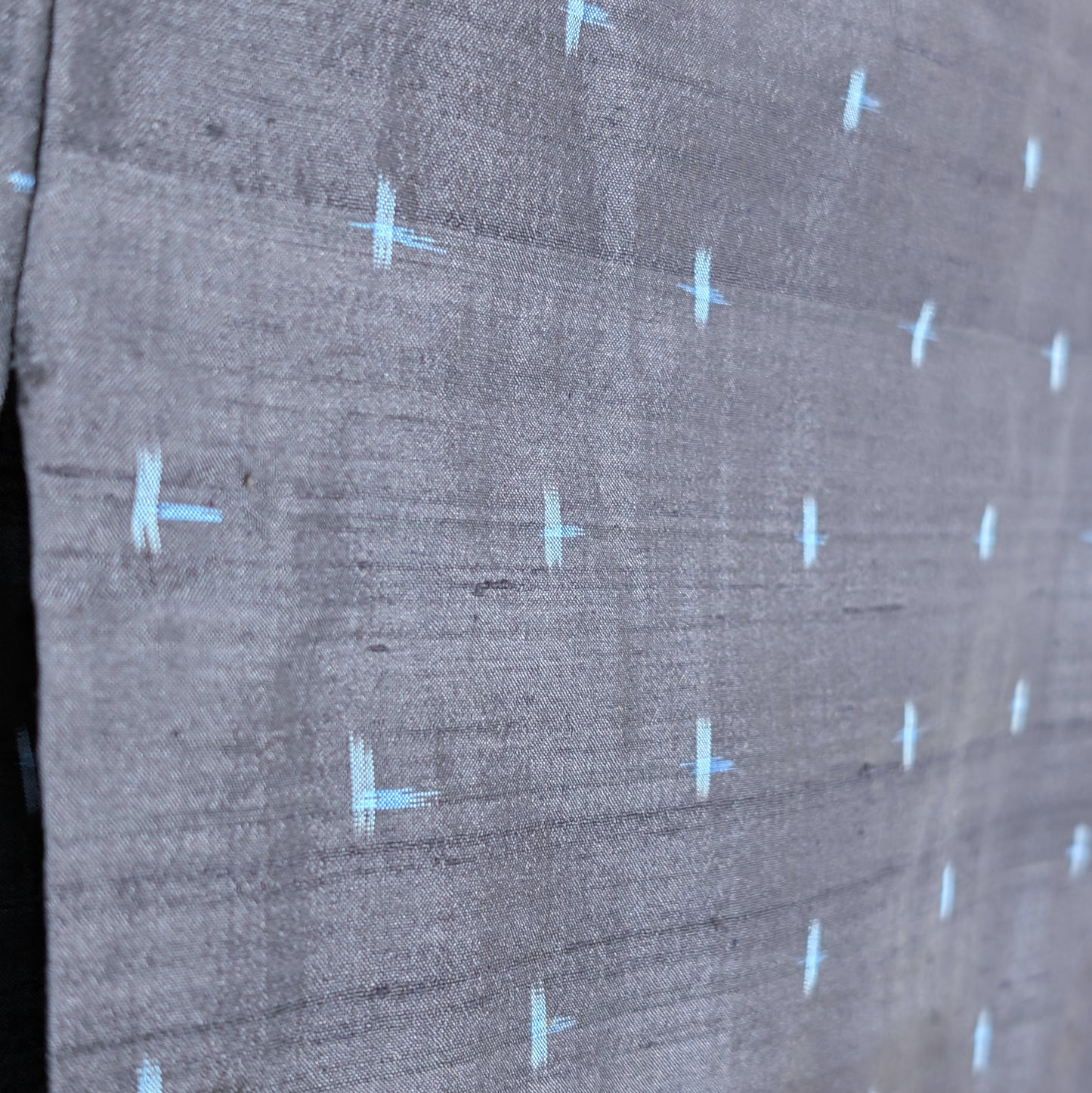 Détail du motif igeta-gasuri bleu clair sur la soie sombre d’un kimono japonais authentique