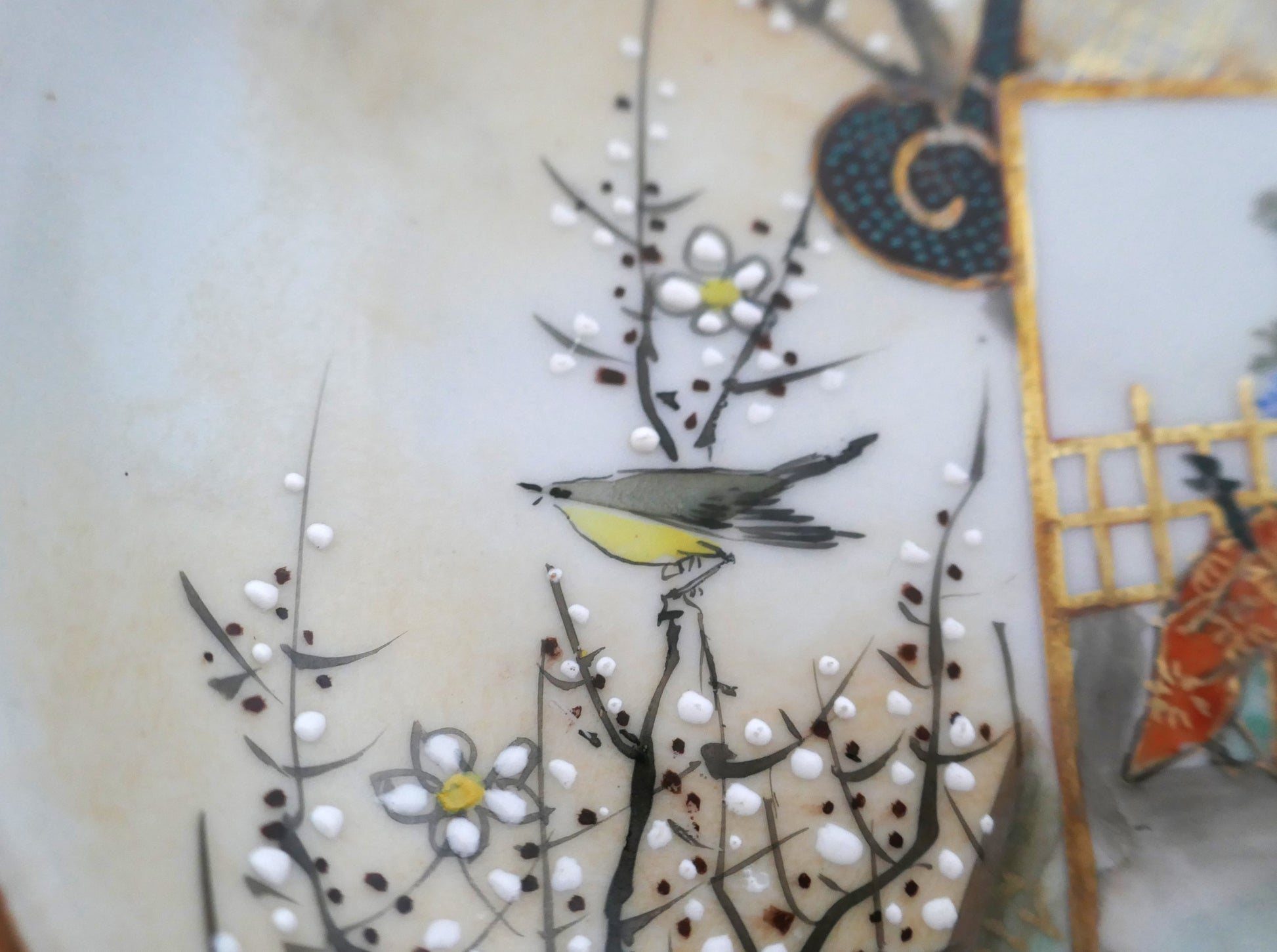 Détail d’un oiseau et de fleurs de prunier en émail blanc en relief sur une assiette Kutani