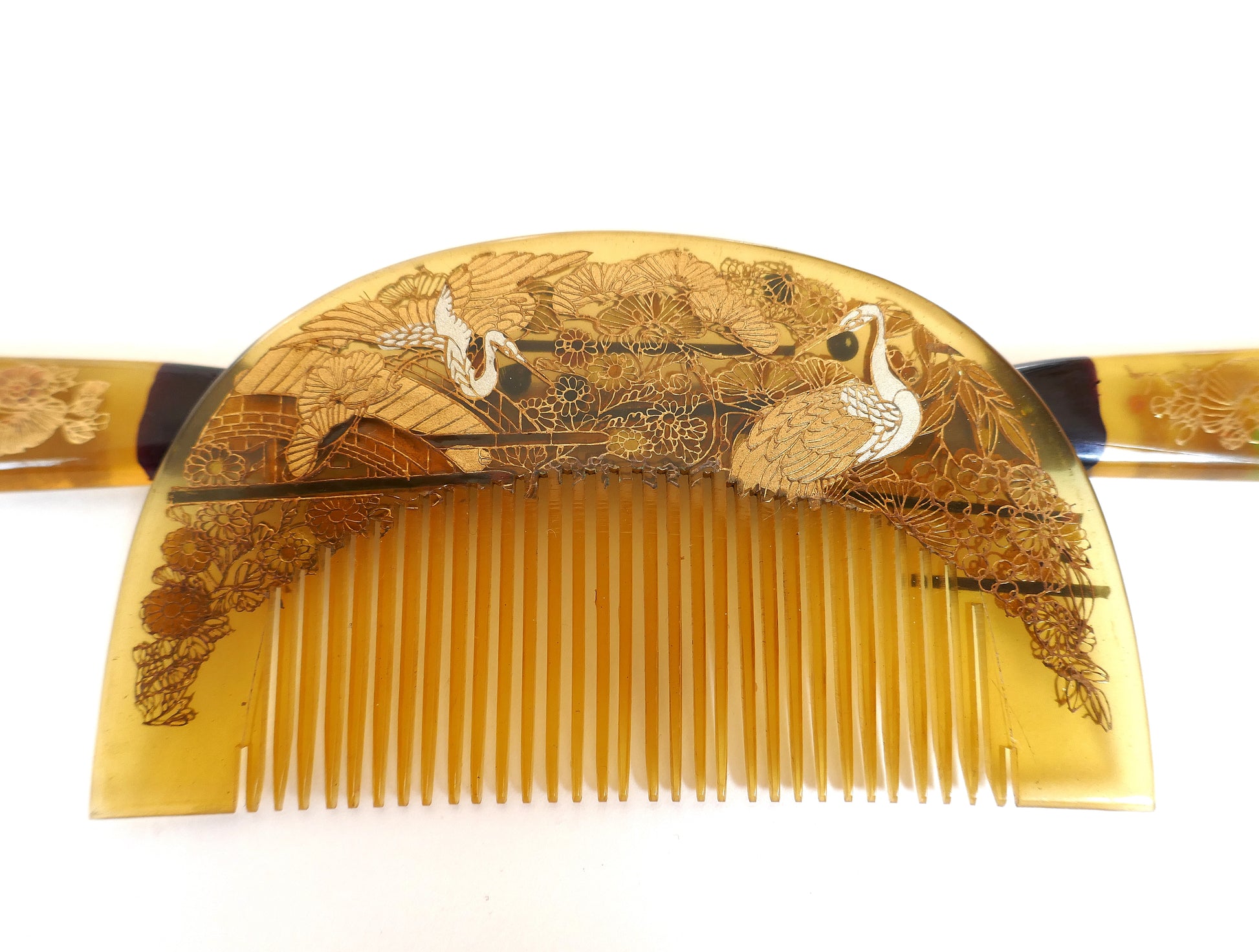 Détail du peigne kushi japonais, décor fin maki-e avec grues et motifs floraux, matière imitation bekko translucide, artisanat Shōwa.