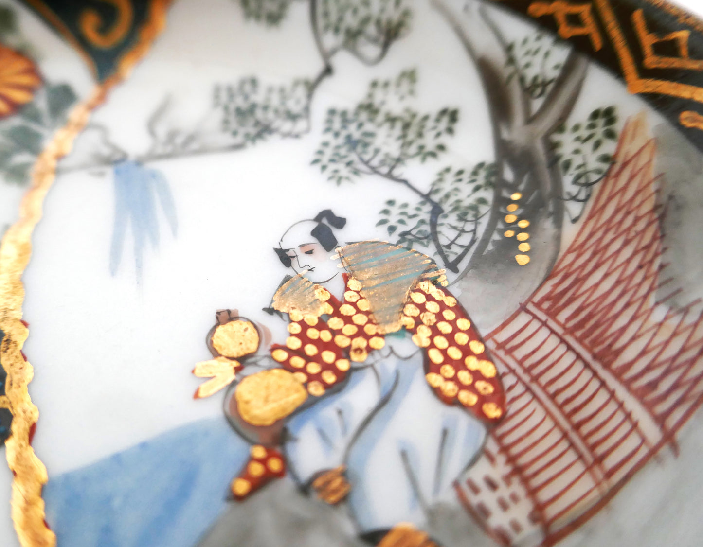 Détail d’un personnage en habit traditionnel doré sur assiette Kutani ancienne