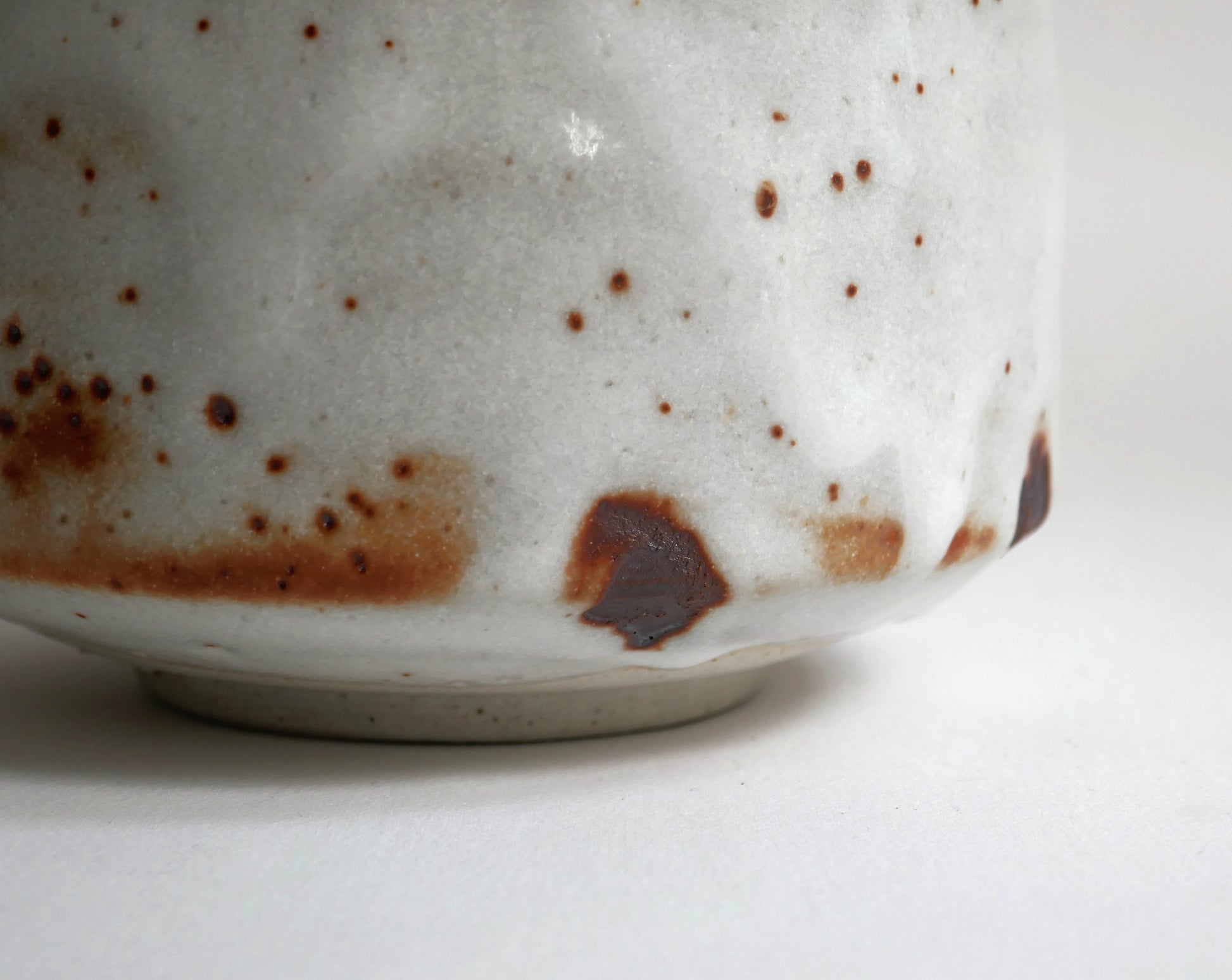 Détail du pied et de la base du chawan Beni Shino, bol matcha japonais avec glaçure blanche Shino et taches brun rouille de cuisson.