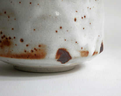 Détail du pied et de la base du chawan Beni Shino, bol matcha japonais avec glaçure blanche Shino et taches brun rouille de cuisson.