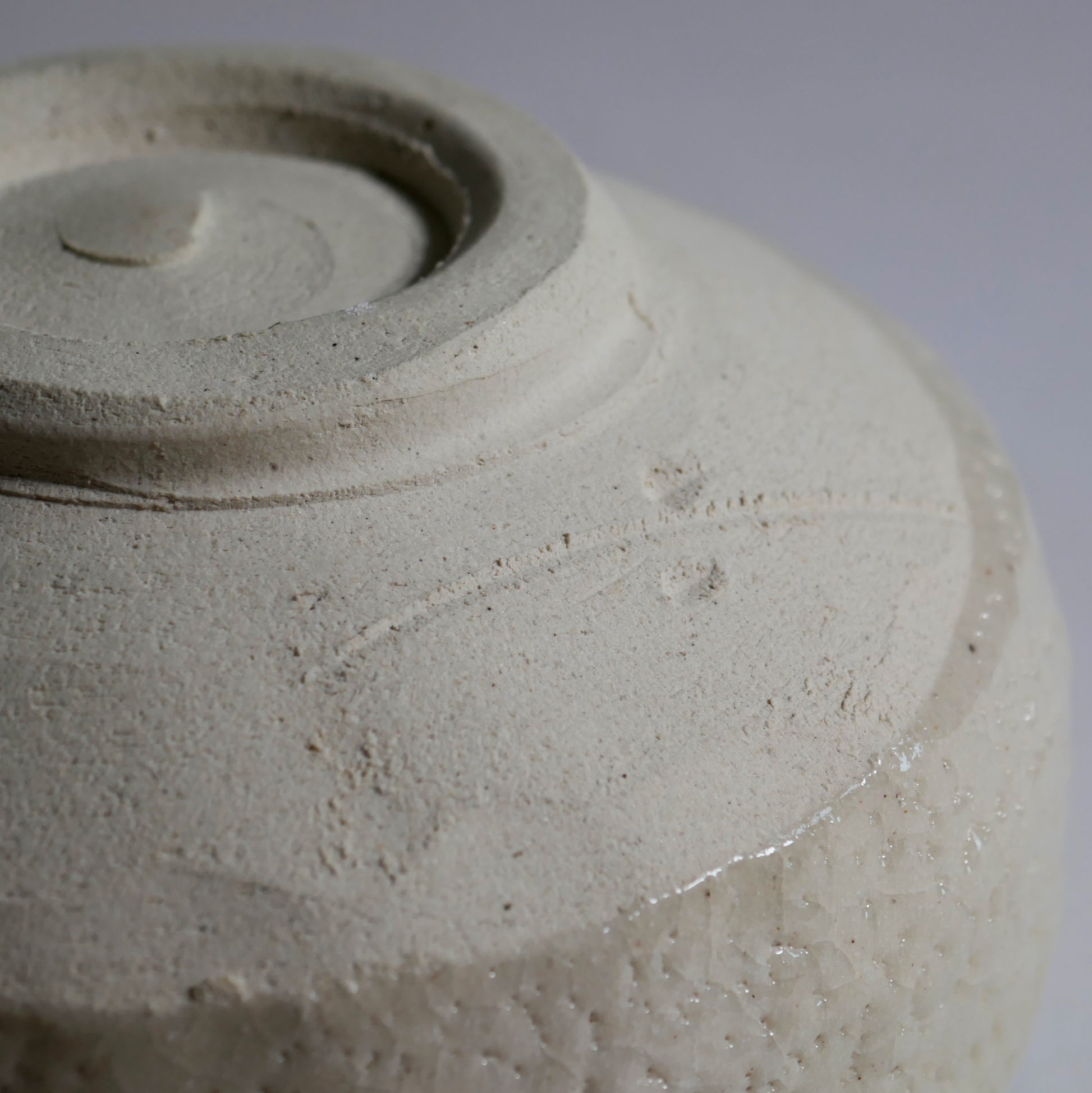 Gros plan sur le pied tourné d’un chawan Oribe en terre claire, céramique Mino-yaki artisanale