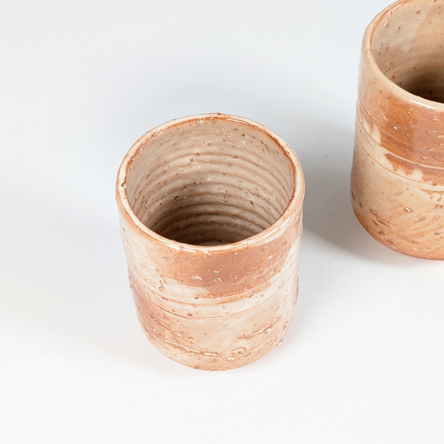 Détail d’une tasse japonaise yunomi en céramique Hagi-yaki, glaçure beige rosée et texture mouchetée artisanale