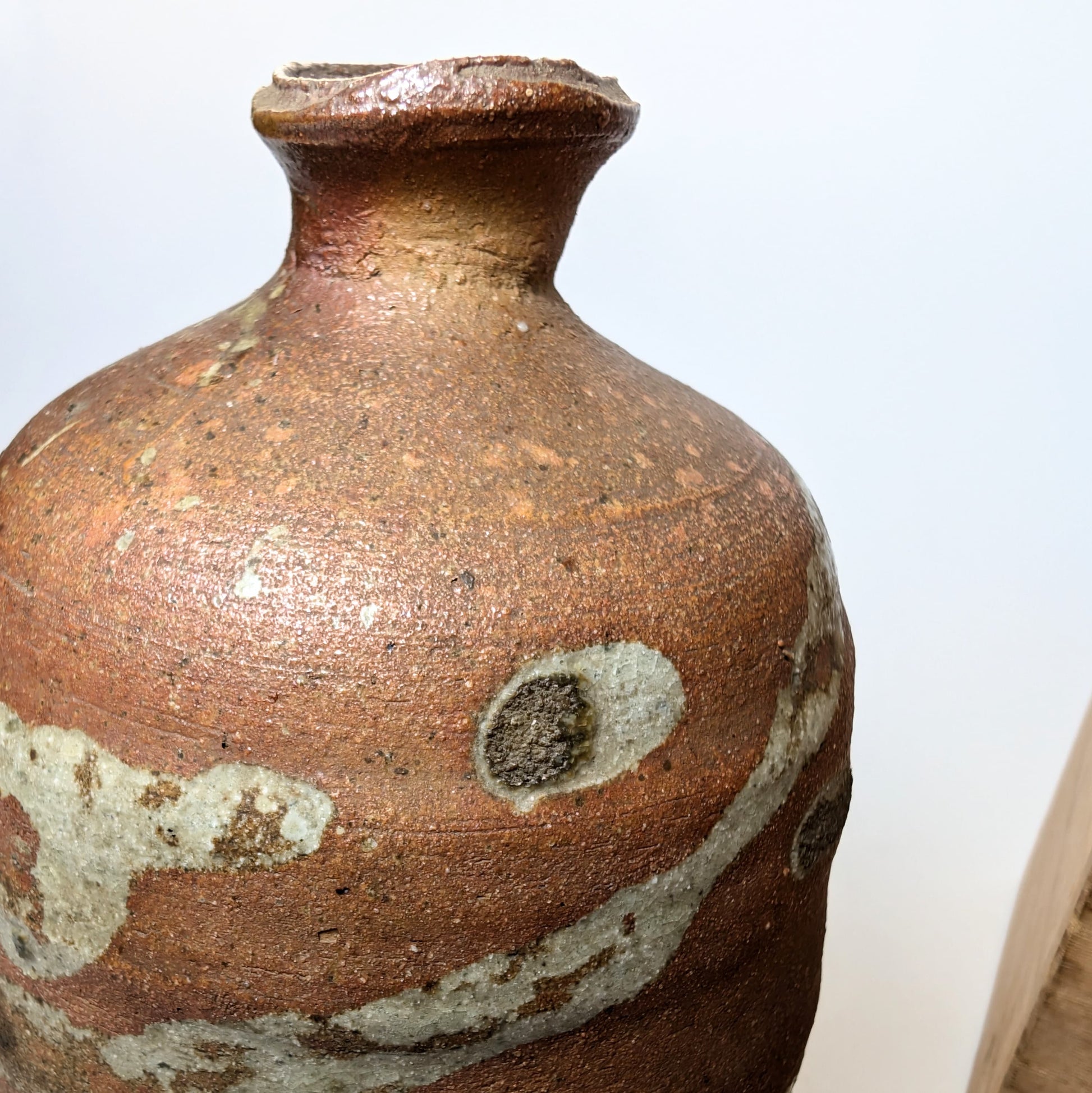 Détail du col d’une Tokkuri japonaise en yakishime, montrant la texture brute et les effets de flamme typiques de la poterie japonaise traditionnelle.