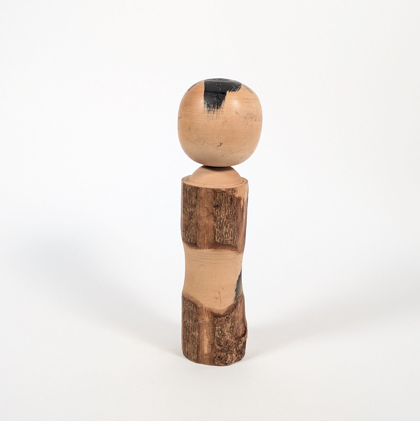 Dos d’une kokeshi omiyage Sato Kôson, corps en bois texturé façon écorce et patine vintage d’art populaire japonais.