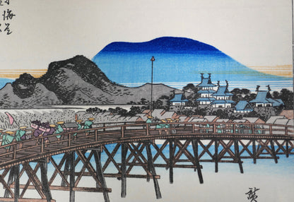 Estampe japonaise de Hiroshige représentant Okazaki et le pont Yahagi, avec le château d’Okazaki et les montagnes bleues en arrière-plan, série des 53 stations du Tōkaidō