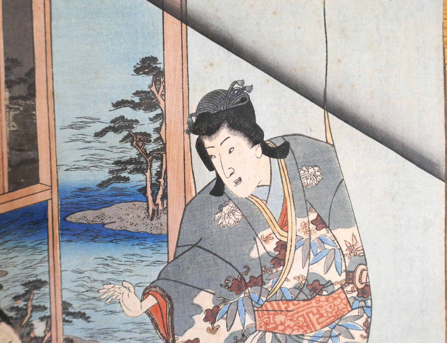 Détail du personnage masculin Genji à droite dans l’estampe de Kunisada II, kimono fleuri et paysage côtier en arrière-plan.