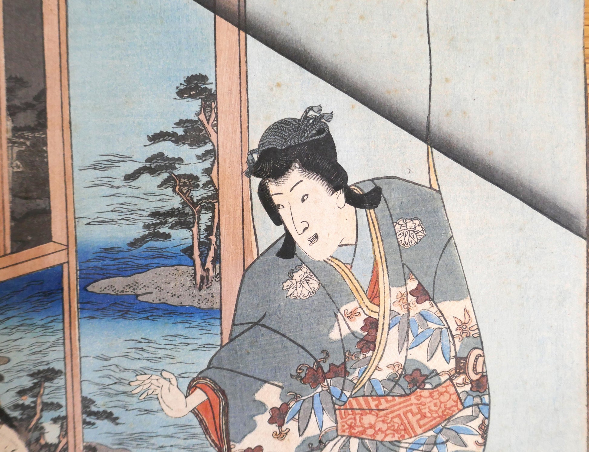 Détail du personnage masculin Genji à droite dans l’estampe de Kunisada II, kimono fleuri et paysage côtier en arrière-plan.