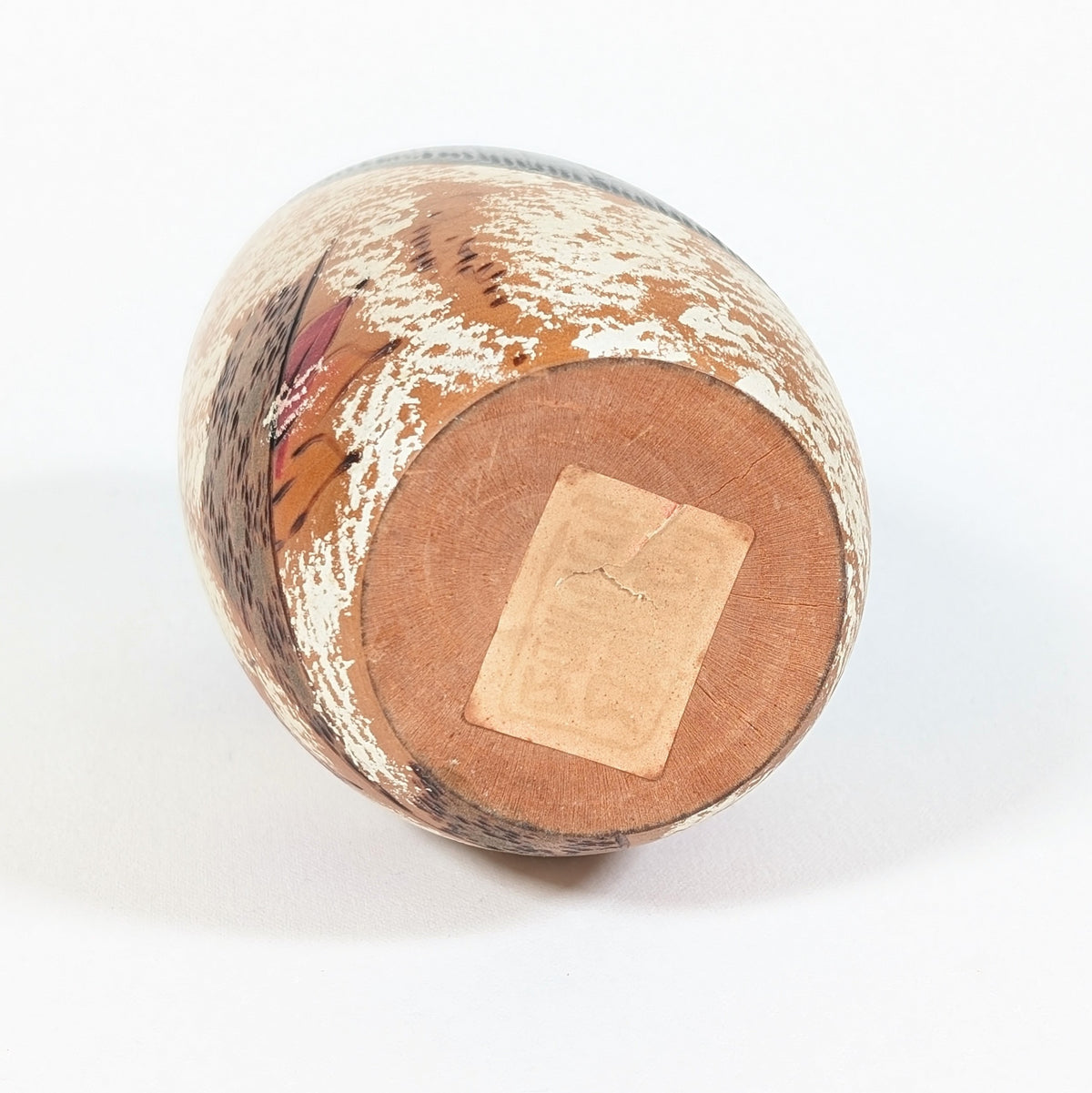 Dessous de la kokeshi japonaise Shôzan en bois, montrant sa base circulaire et l’ancienne étiquette de l’atelier Usaburo.