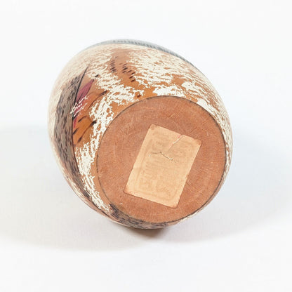 Dessous de la kokeshi japonaise Shôzan en bois, montrant sa base circulaire et l’ancienne étiquette de l’atelier Usaburo.