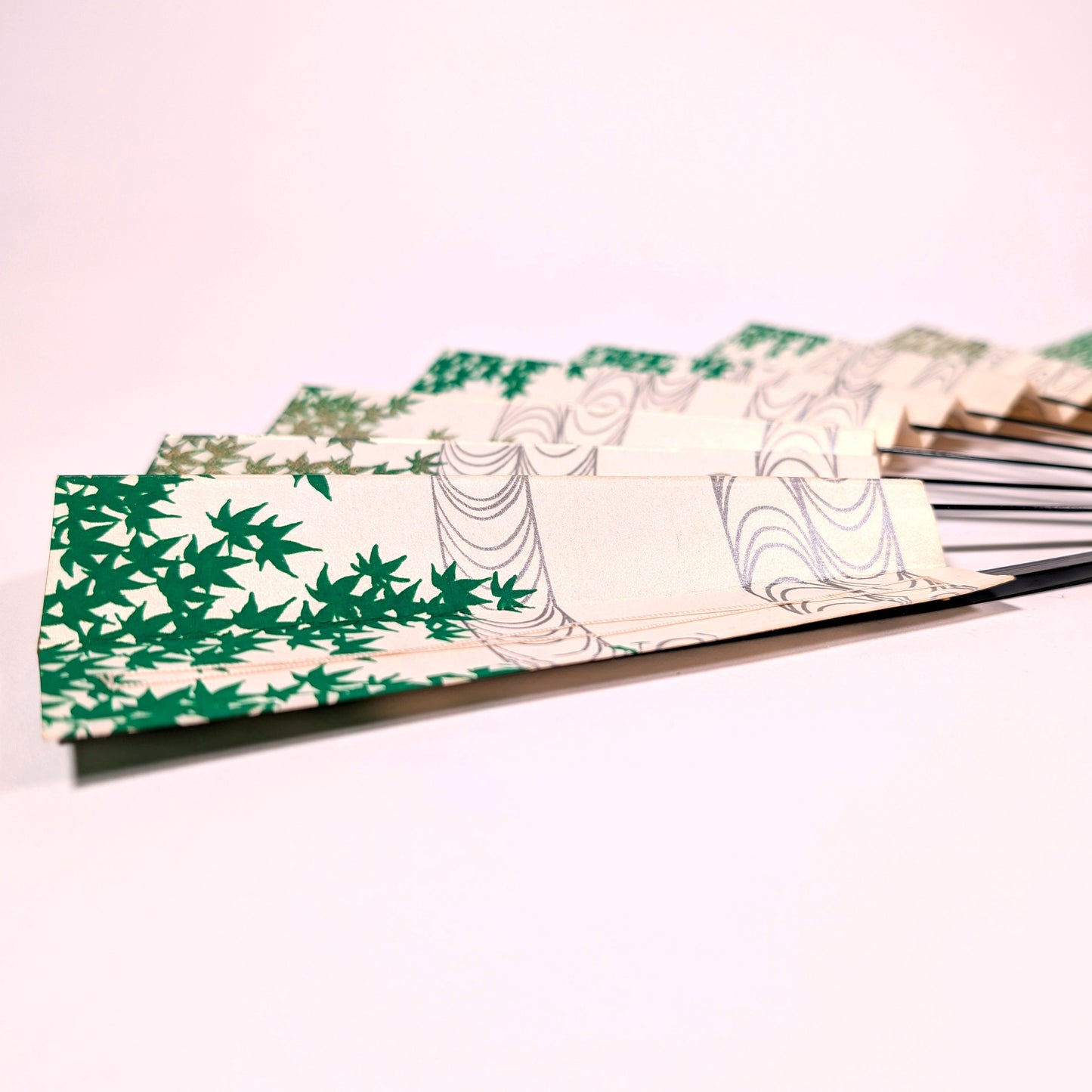 Éventail japonais sensu entrouvert, décoré de feuilles d’érable vert et d’un motif d’eau courante sur fond ivoire.