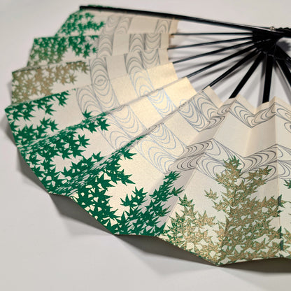Vue rapprochée d’un éventail japonais vert, ivoire et or pâle à motif d’aomomiji et de ryūsui.