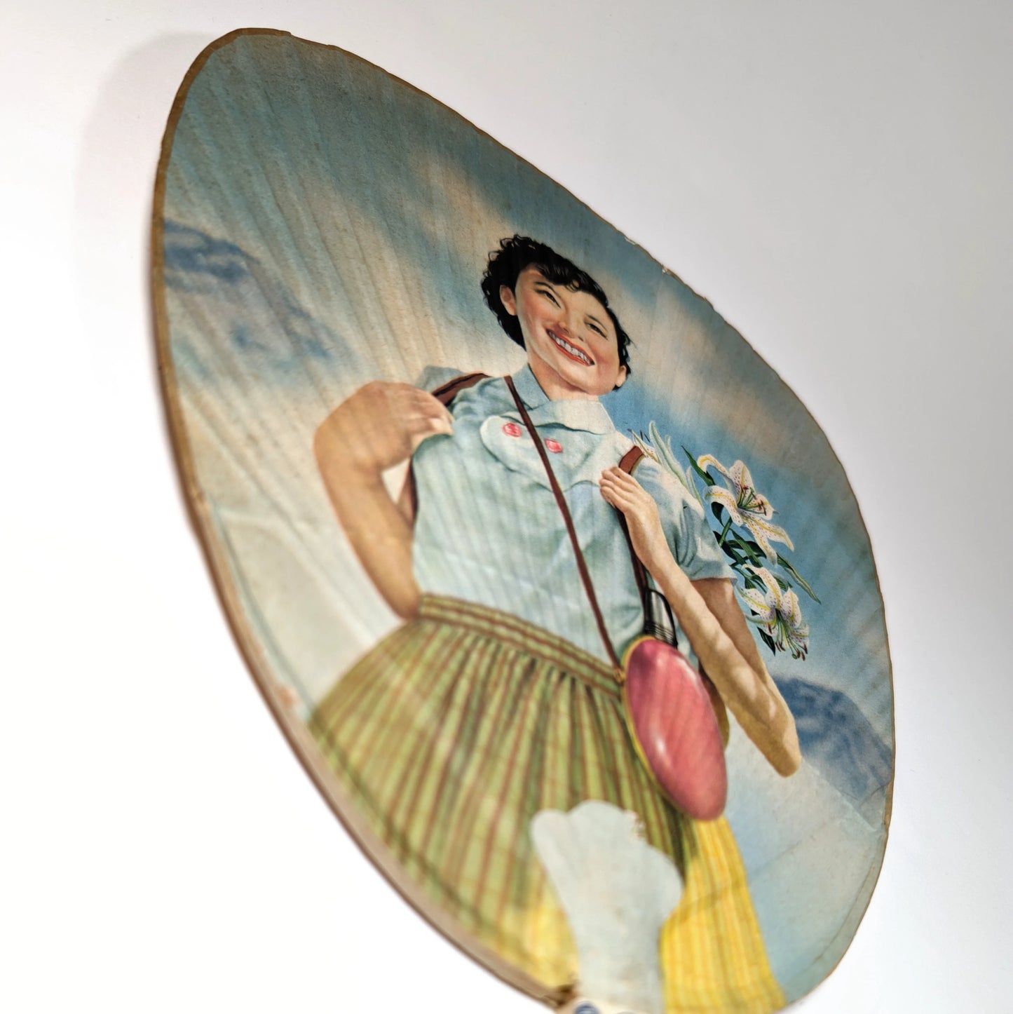 vue en perspective d’un éventail uchiwa vintage japonais montrant les reliefs du papier et l’illustration colorée