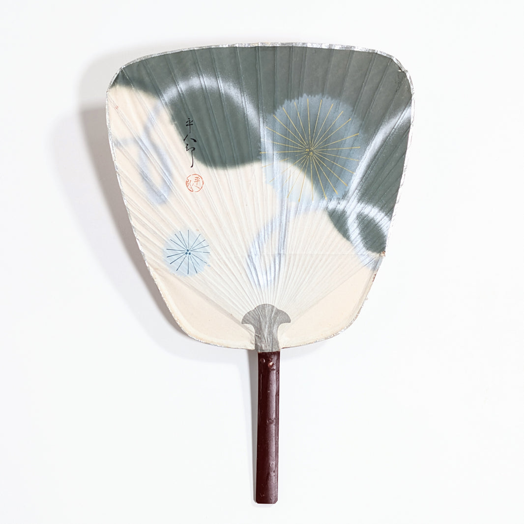 Uchiwa japonais ancien blanc, vert gris et argenté, décoré de motifs hanabi dorés et bleus.