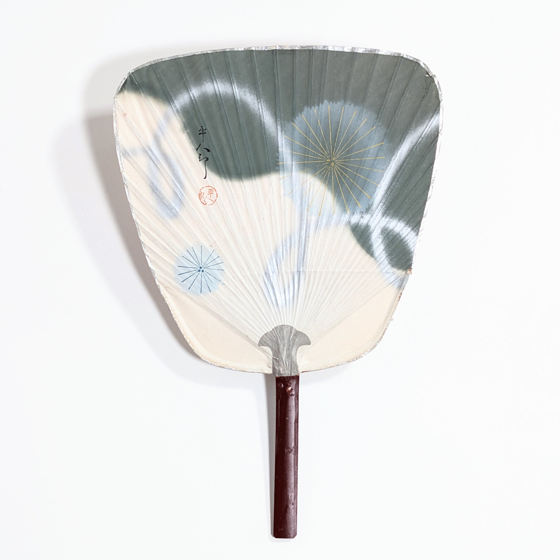 Uchiwa japonais ancien blanc, vert gris et argenté, décoré de motifs hanabi dorés et bleus.