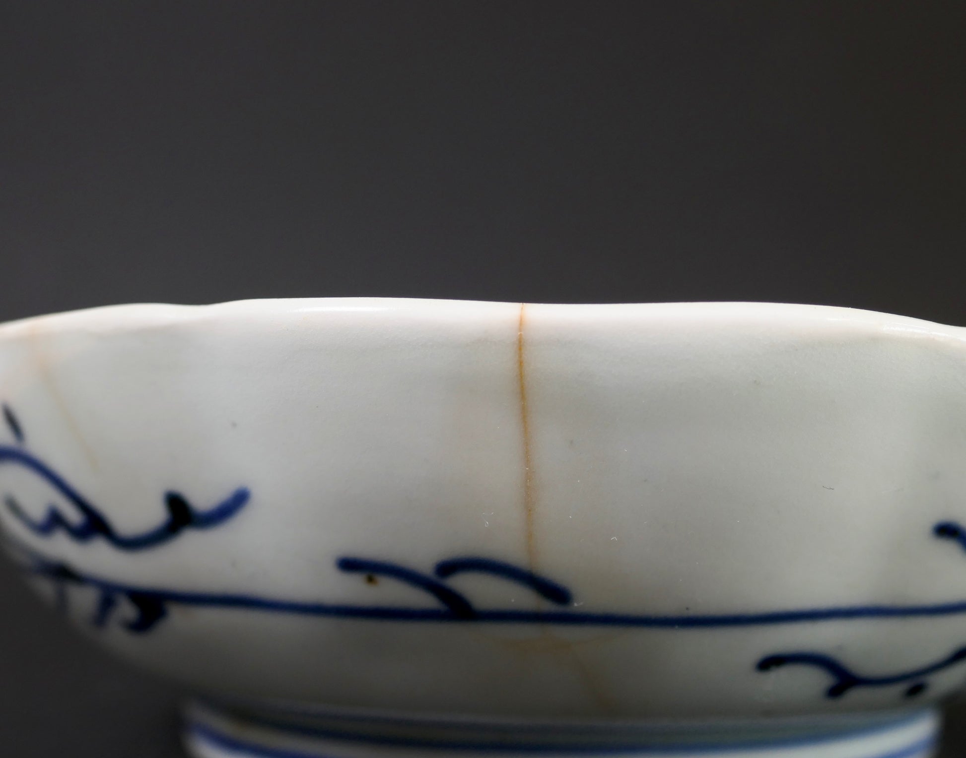 Fine fêlure ancienne visible sur le bord d’une assiette japonaise en porcelaine bleu et blanc Imari