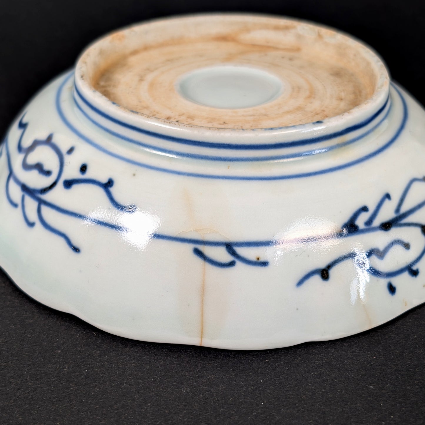 Gros plan d’une fêlure traversante ancienne et de traces de consolidation sur une assiette japonaise Imari