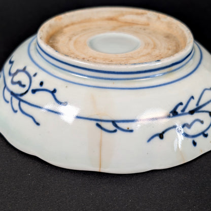 Gros plan d’une fêlure traversante ancienne et de traces de consolidation sur une assiette japonaise Imari