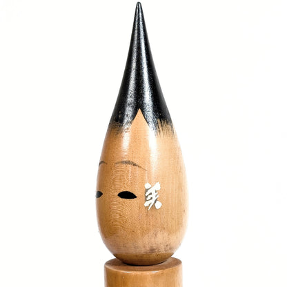 Gros plan du visage d’une poupée japonaise fude kokeshi en bois, kanji 美 peint, style Shōwa