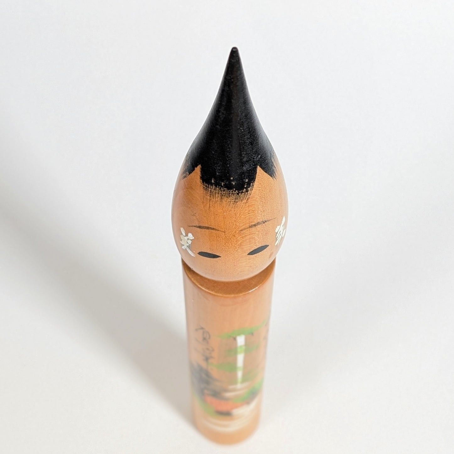 Vue plongeante du dessus d’une poupée japonaise fude kokeshi en bois, visage et coiffure laquée